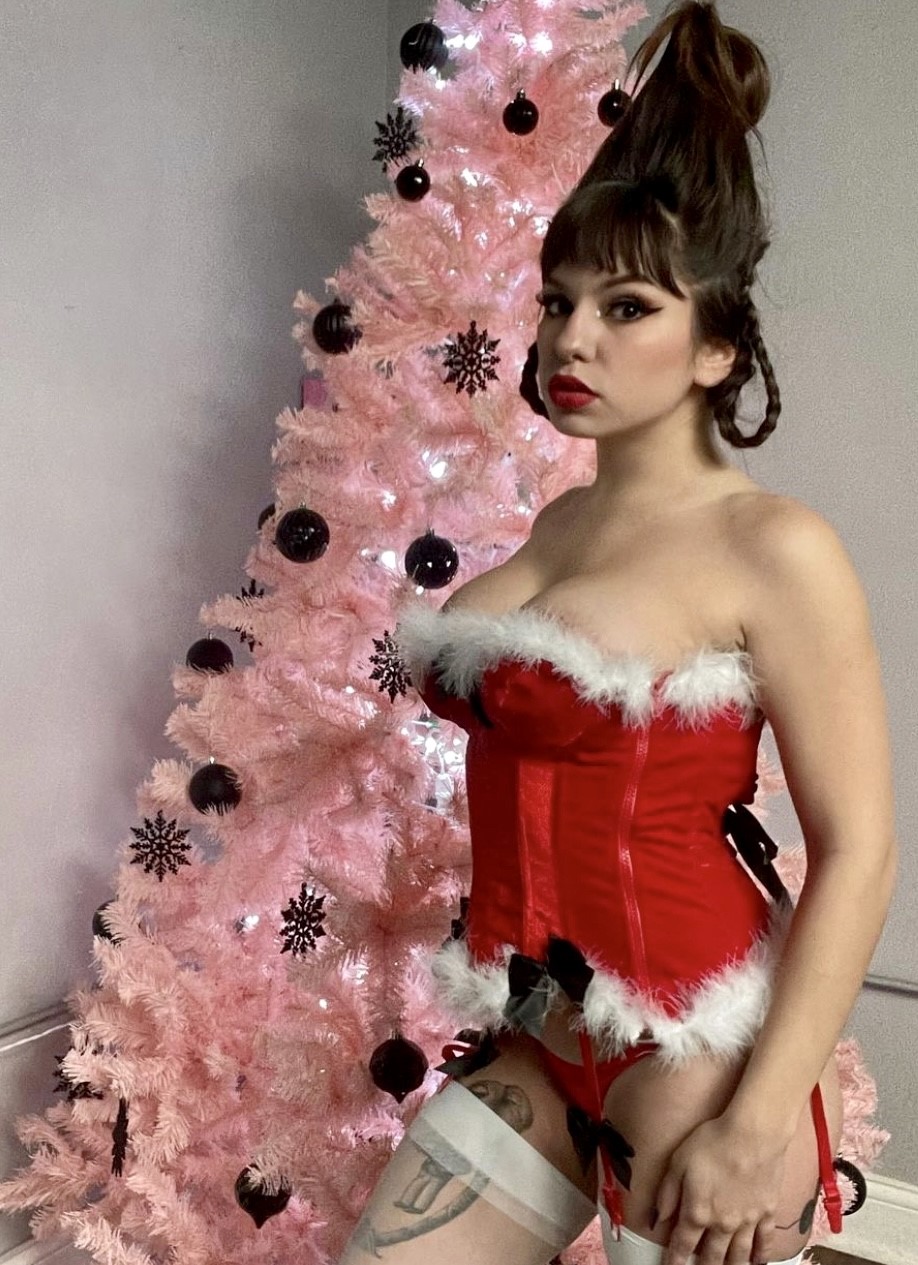 a girl in a red dress standing near a Christmas tree